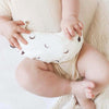 Baby met warmtekussen 'To the Moon White' op buikje, gevuld met 100% biologische gereinigde kersenpitten van Warmtemaantje