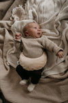 Baby met warmtekussen 'Velours Cream' op buikje, gevuld met 100% biologische gereinigde kersenpitten van Warmtemaantje